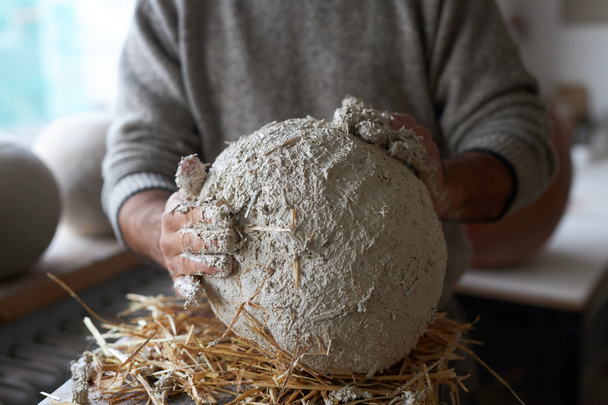 Hände formen Lehm im Urnen-Workshop